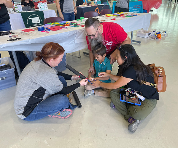 Teachers help a young student with a STEM activity during NASA's STELLAR program geared toward teachers learning from NASA personnel to implement those lessons into their classroom curriculum. 