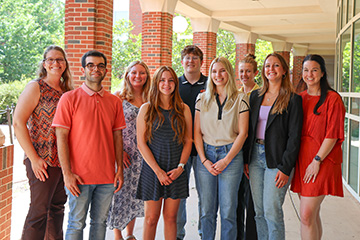 Group of students standing together outside a campus building during a summer research program.