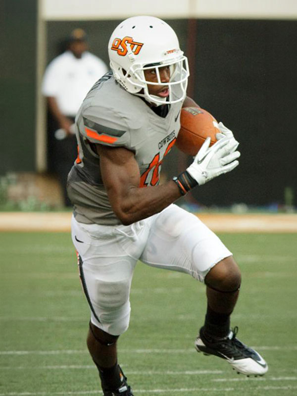 Oklahoma State Cowboys football player in a gray practice uniform running with a football during practice.