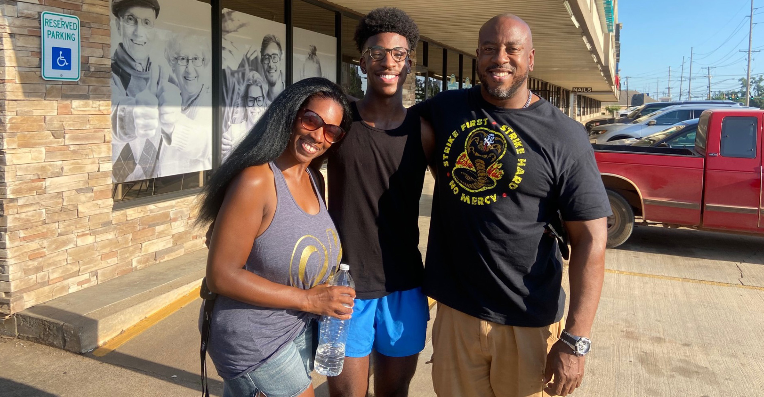Three family members pose for a group photo outside of a business.