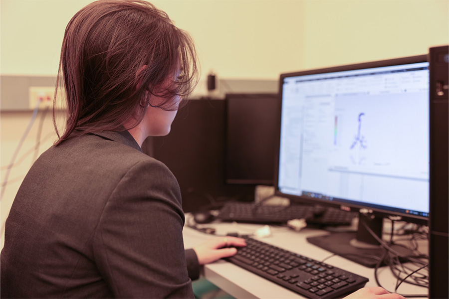 A woman sits at a computer screen with a computer model of human organs on the screen. 