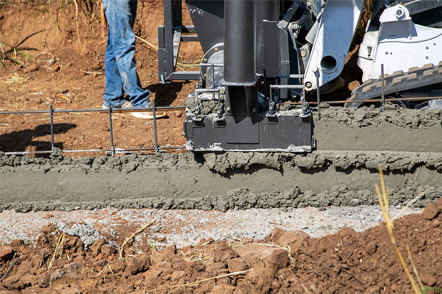 The image depicts a construction site where four individuals are engaged in pouring concrete.