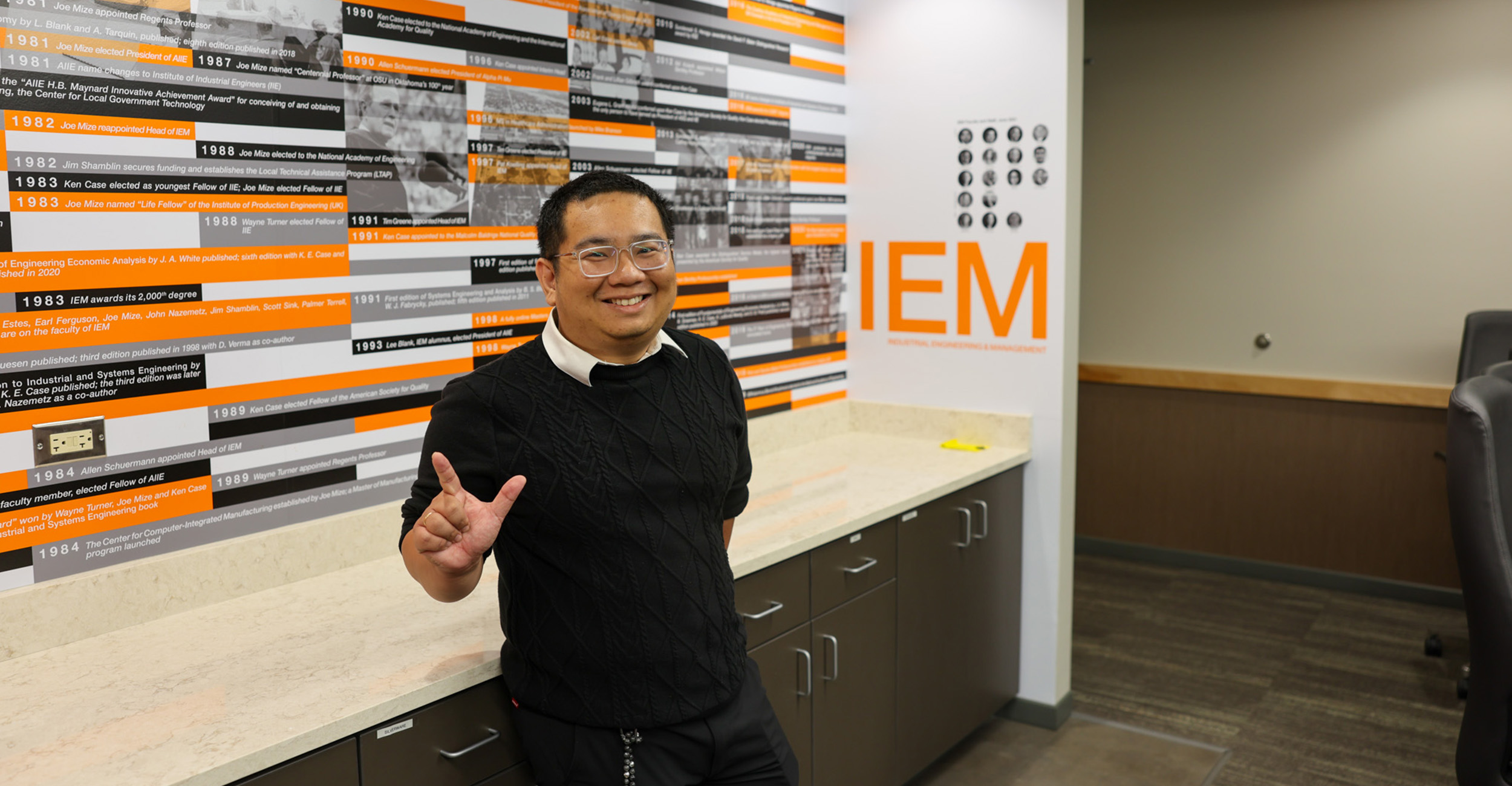 A color photograph shows a smiling person standing in an industrial engineering department lobby.