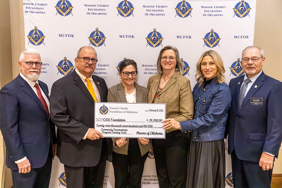 Six people dressed in suits and business casual clothing pose for a photo with a check of $29,700, which was donated by the Masonica Charitable Foundation of Oklahoma to fund part of an expansion of the mobile integrated healthcare program in Oklahoma over the next five years.