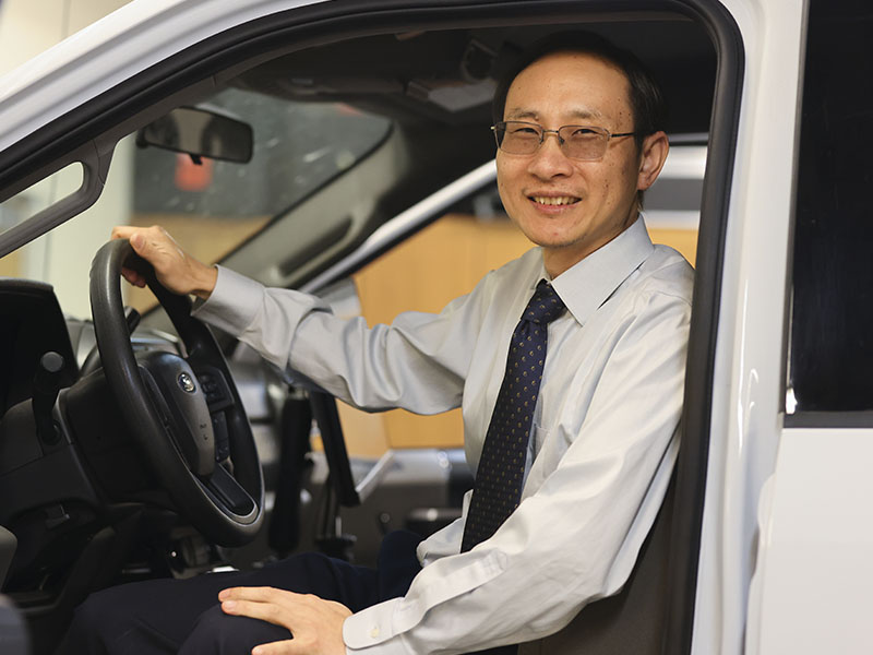 A researcher sits in the driver's seat of a pickup truck equipped with data collection technology used for transportation and pavement research.