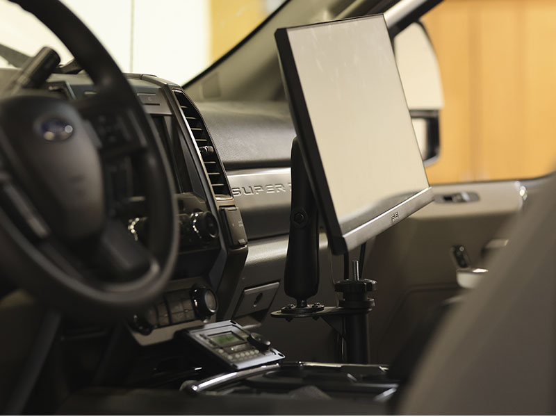 A computer monitor and electronic equipment are mounted inside a pickup truck, creating a mobile workspace for roadway data collection and analysis.