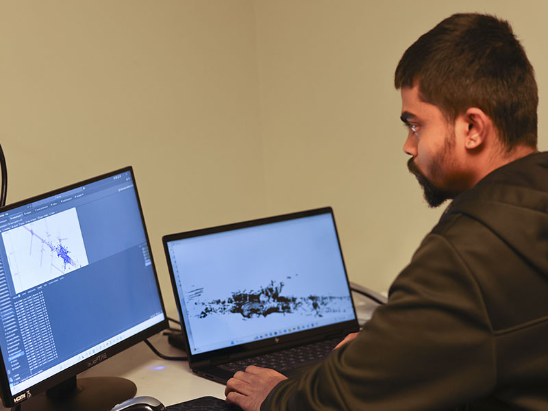A student works at a computer workstation displaying data visualizations and analysis results used in transportation engineering research.