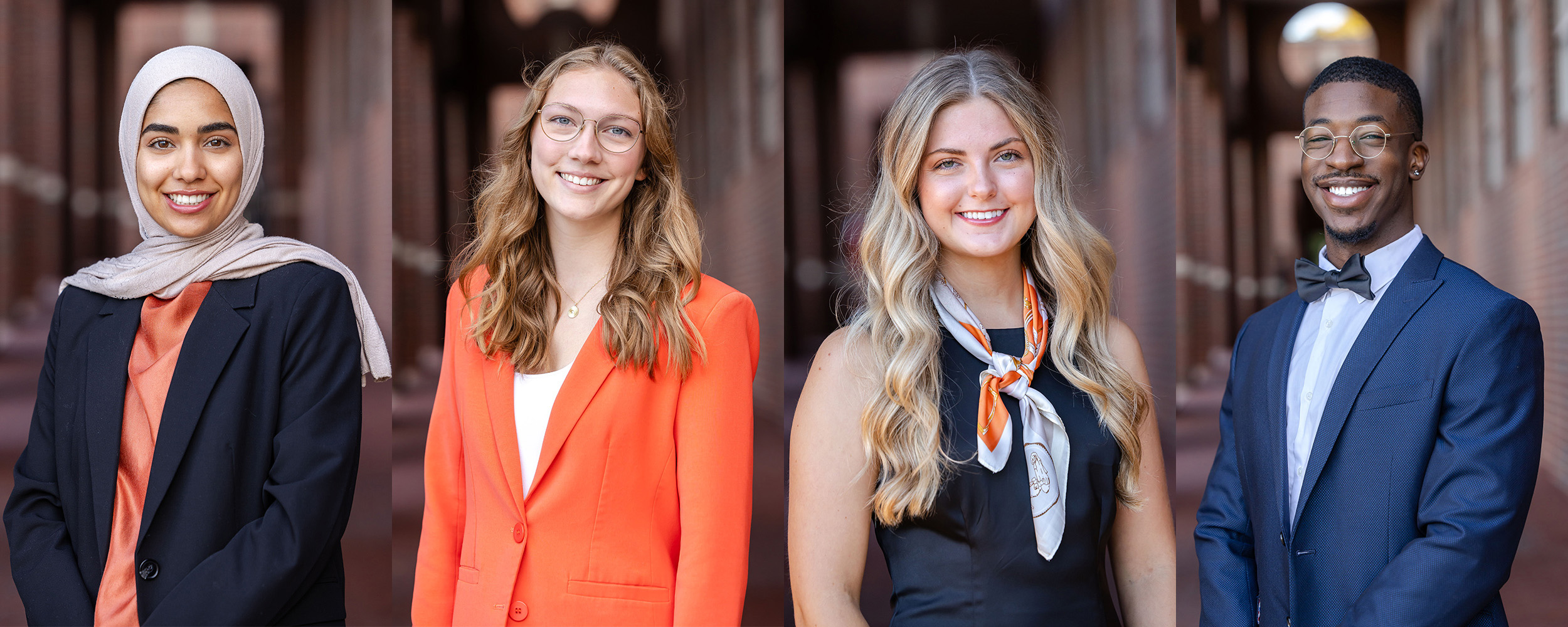 A group of four people stand side by side in professional attire along an outdoor brick walkway.