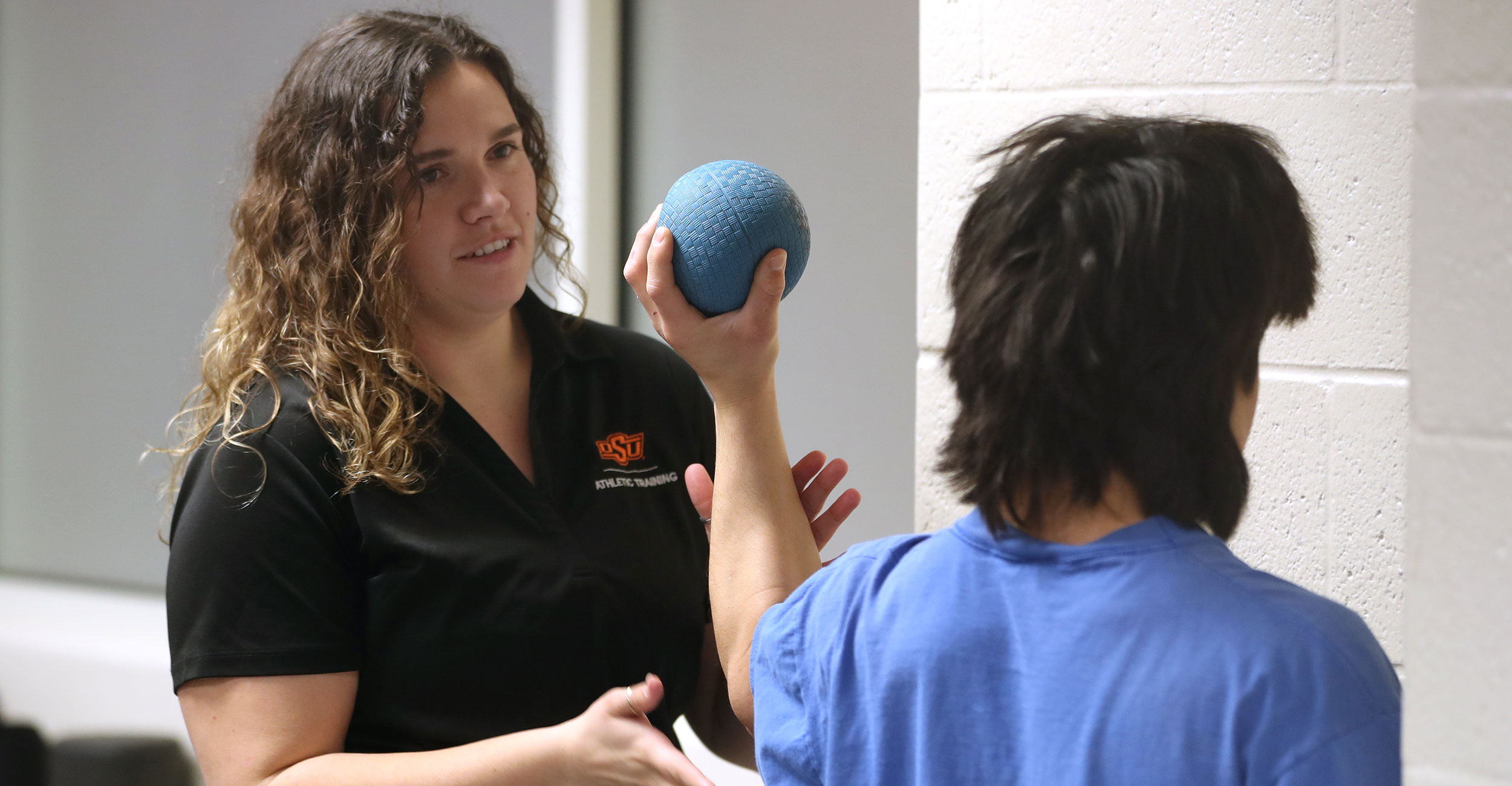 OSU-CHS athletic training student Cheyann Sales works with an OSU wrestling athlete at Gallagher-Iba Arena.