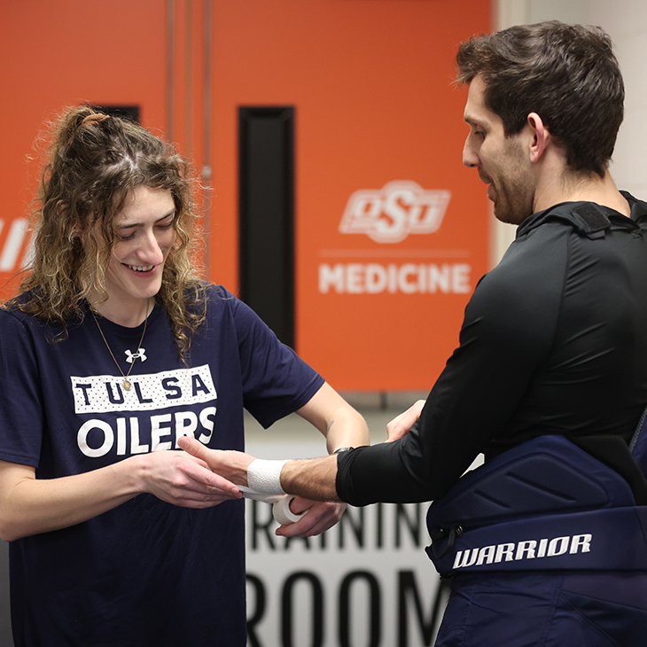 Athletic trainer Sara Latos tapes the wrist of Tulsa Oilers hockey player Duggie Lagrone in the training room.