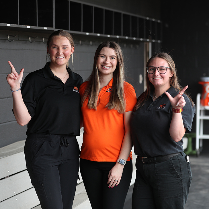Athletic training students Kaleigh Hanzlick (left), Tatum Komlodi and Samantha Renson (right) in the OSU Cowgirls softball dugout.