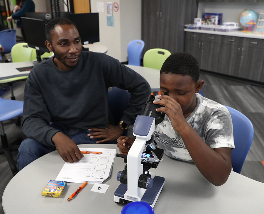 OSU-CHS Biomedical Sciences graduate student Thomas Momanyi (left) helps a boy use a microscope during a STEM outreach event hosted by the Biomedical Sciences Graduate Student Association at the Salvation Army North Mabee Boys & Girls Club in Tulsa.