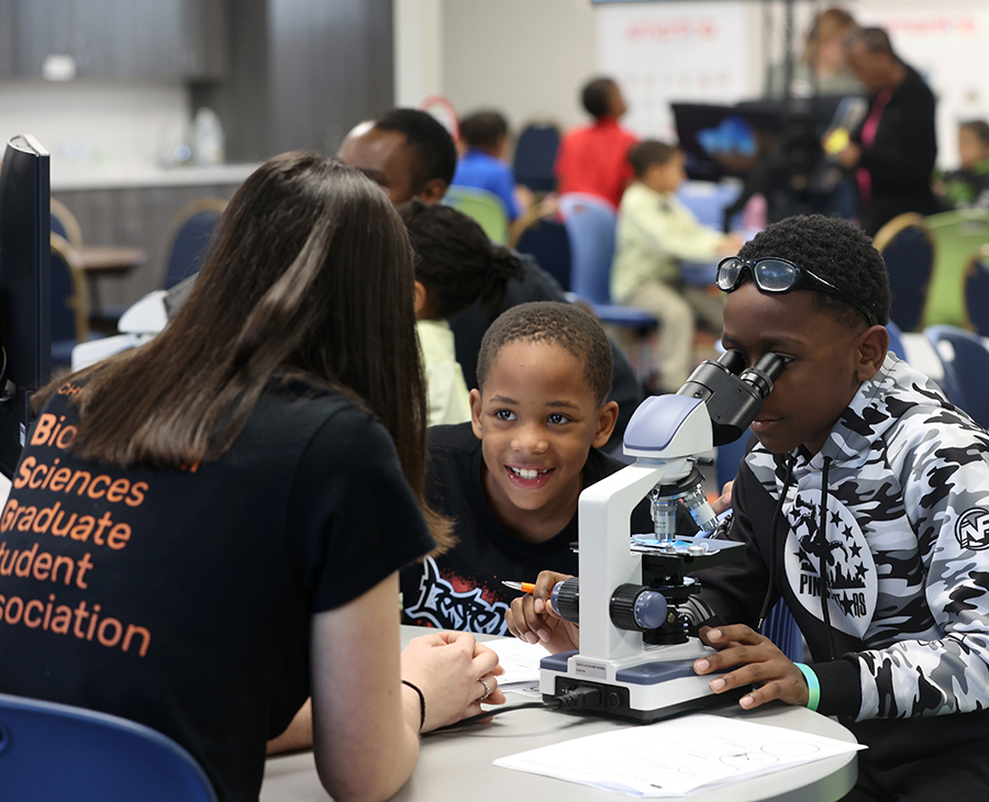 An OSU-CHS Biomedical Sciences graduate student helps young students use a microscope during a STEM outreach event hosted by the Biomedical Sciences Graduate Student Association at the Salvation Army North Mabee Boys & Girls Club in Tulsa.