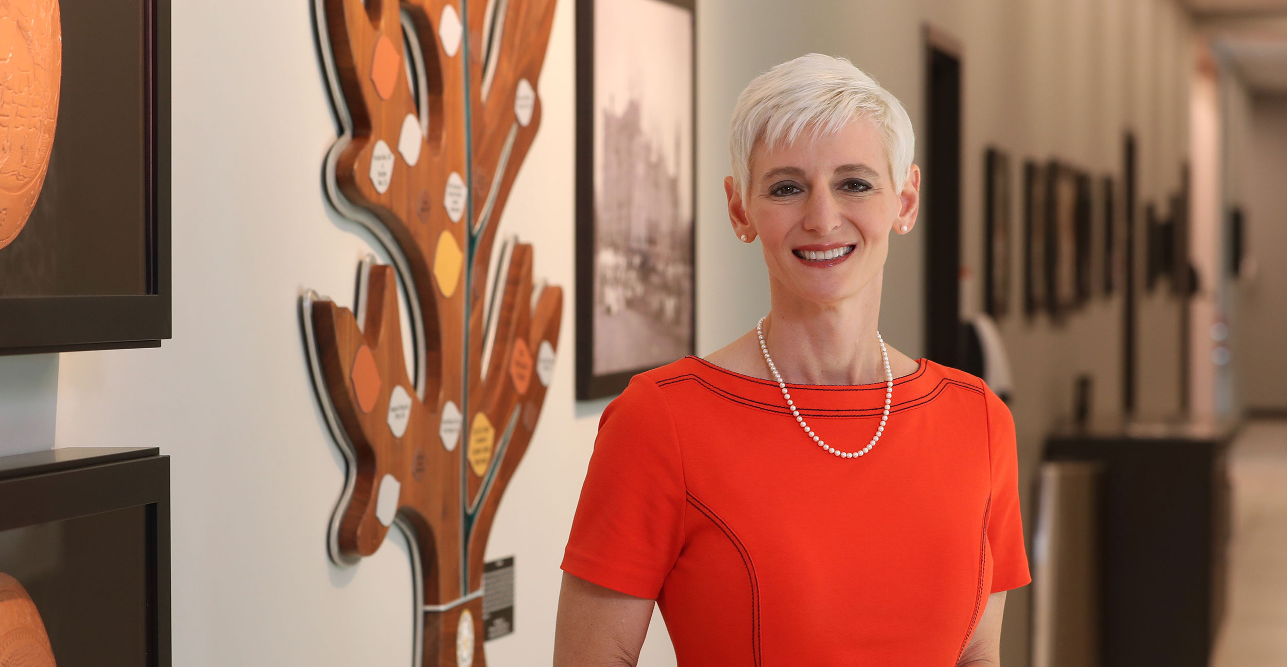 Dr. Natasha Bray, dean of the OSU College of Medicine at the Cherokee Nation, stand in front of the donor wall on the campus in Tahlequah.