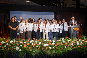 A group of Oklahoma State University Center for Health Sciences students stand together on a stage during the Orange Impact fundraising event on the O.S.U.C.H.S. campus.