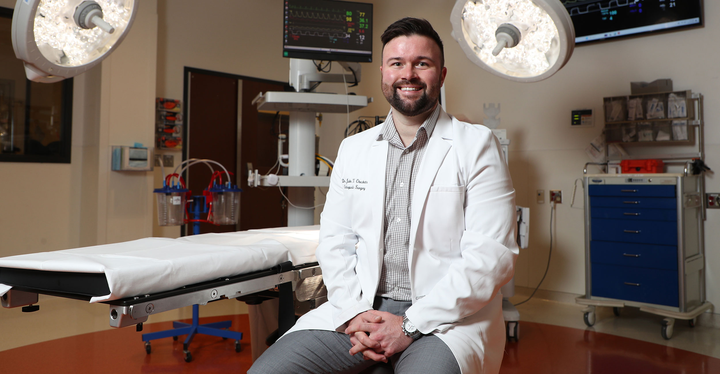 Dr. Jake X. Checketts, an OSU-COM alumnus and OSU Medicine resident, sits in the surgical suite in the simulation hospital at OSU Center for Health Sciences. Checketts was recently awarded the 2024 Outstanding Resident of the Year from the American Osteopathic Foundation and the American Osteopathic Academy of Orthopedics.