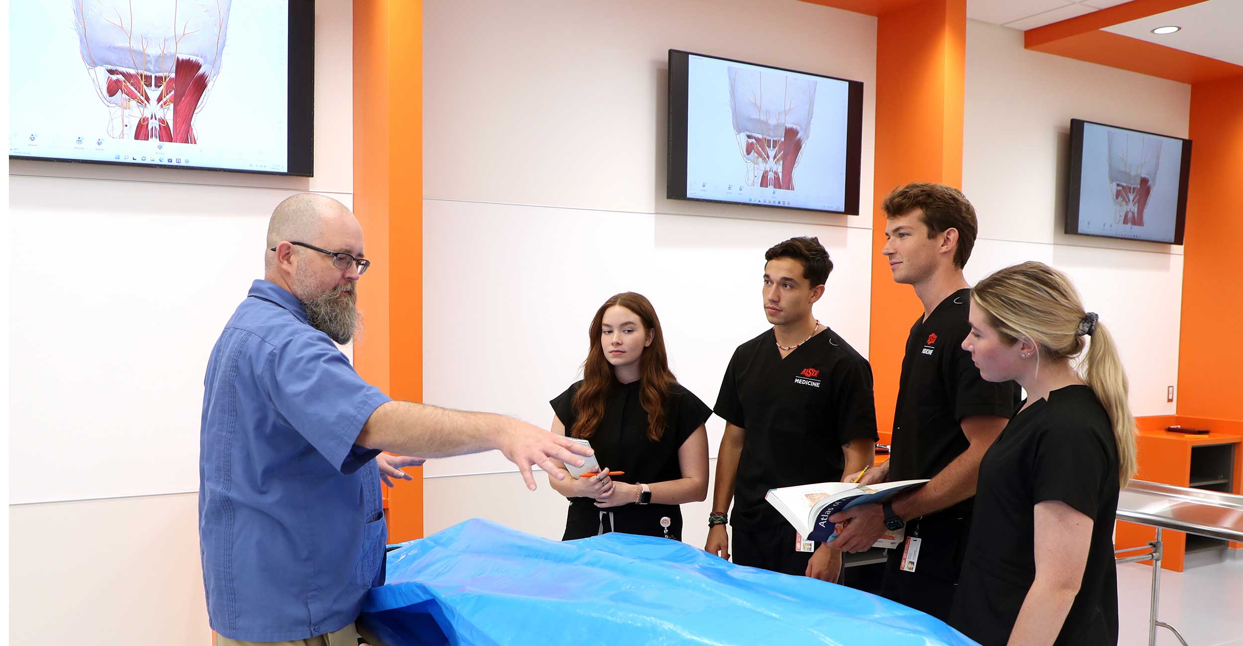 Dr. Ian Browne (left) talks with medical students Kathryn Smith, Jordan Valenzuela, Ryan Sherry and Keri Mitchell (right) during orientation in the new anatomy lab in North Hall on the Center for Health Sciences camp