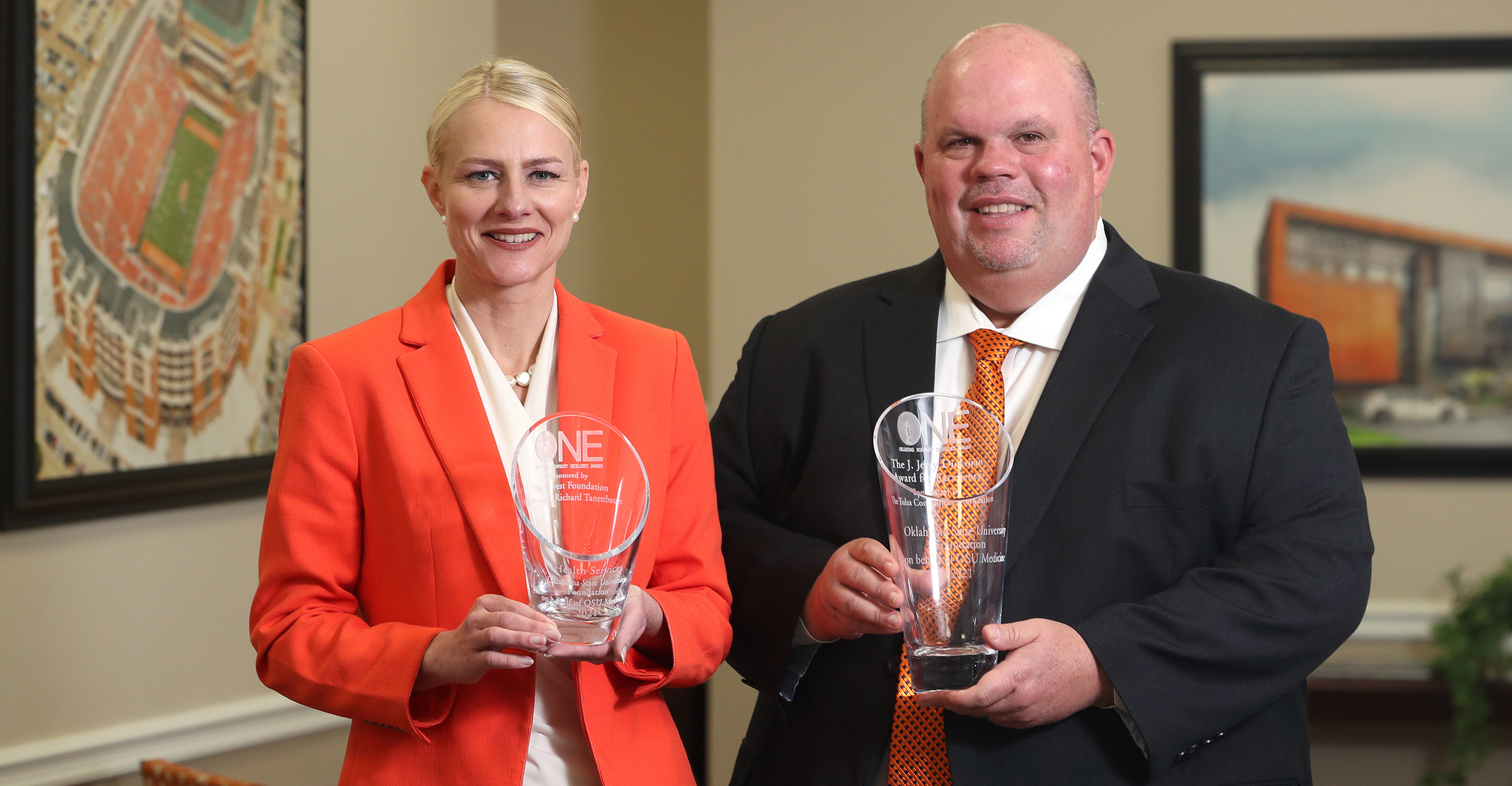 Dr. Kayse Shrum (left) and Dr. Johnny Stephens hold awards given to OSU Center for Health Sciences at the recent ONE Awards.