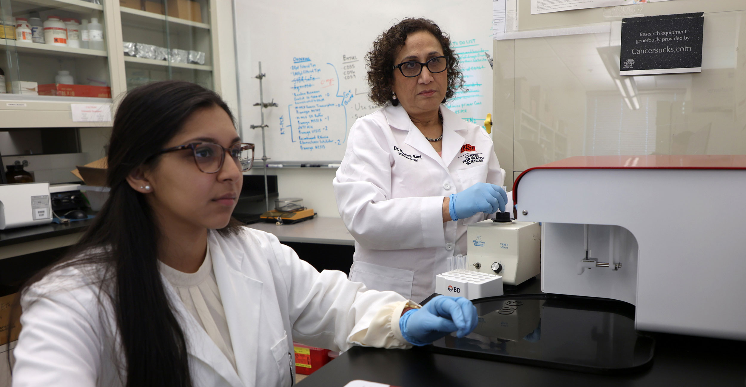 Biomedical Sciences student Sachi Pathak (left) and Rashmi Kaul, Ph.D., use a flow cytometer to analyze cells in Kaul's lab at OSU Center for Health Sciences.