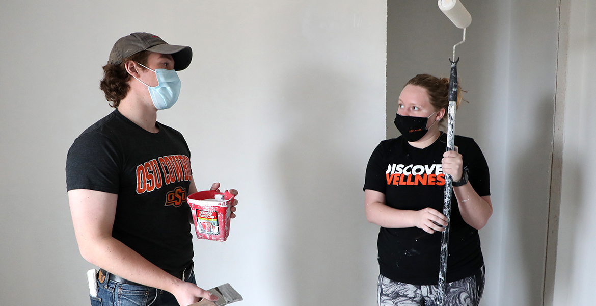 OSU College of Osteopathic Medicine students Hunter Meyers (left) and Shelby Cummins (right) paint a house as part of a volunteer project for Tahlequah Area Habitat For Humanity.