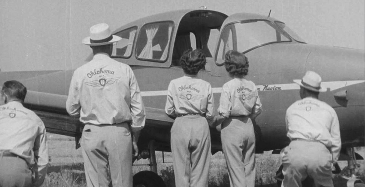 Four "flying farmers" examine a small plane