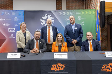 Six people, including Oklahoma State University representatives and Oklahoma CareerTech leaders, pose for a signing ceremony in front of an Oklahoma CareerTech backdrop.