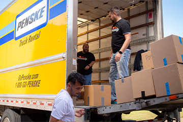 Volunteers unload boxes from a Penske truck to support a community food pantry.