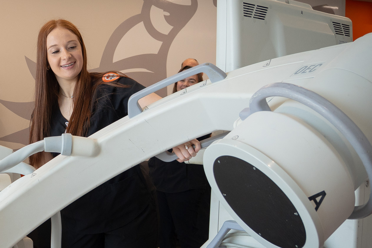 Radiologic student standing next to medical equipment.