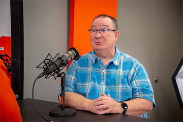 man speaking into a microphone at a table