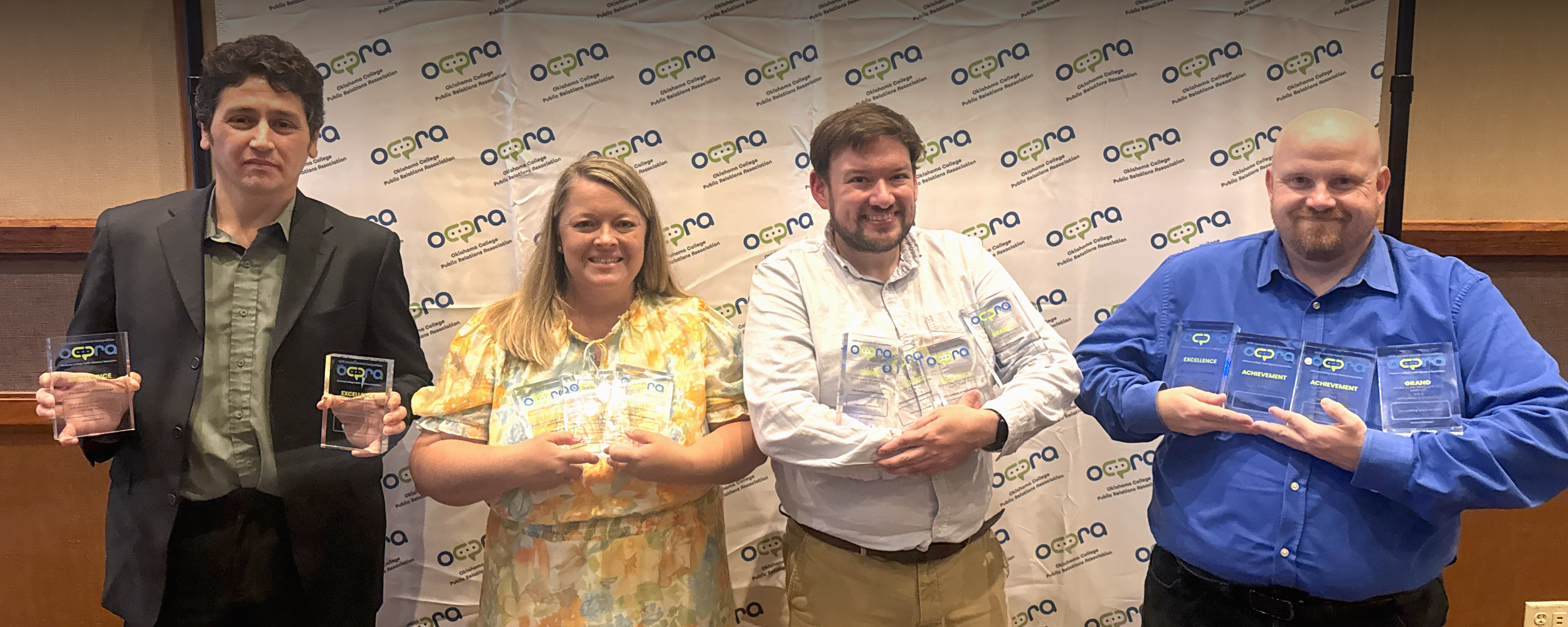 Four members of the OSUIT marketing team stand together holding statewide communications awards.