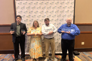 Four members of the OSUIT marketing team stand together holding framed statewide communications awards.