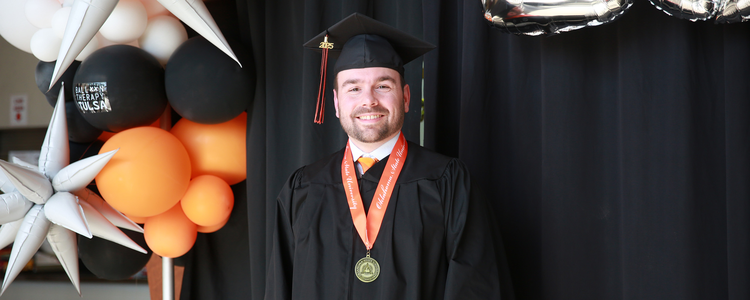 Joshua Buck, in his cap and gown, posed at the spring 2025 graduation commencement ceremony in Tulsa.