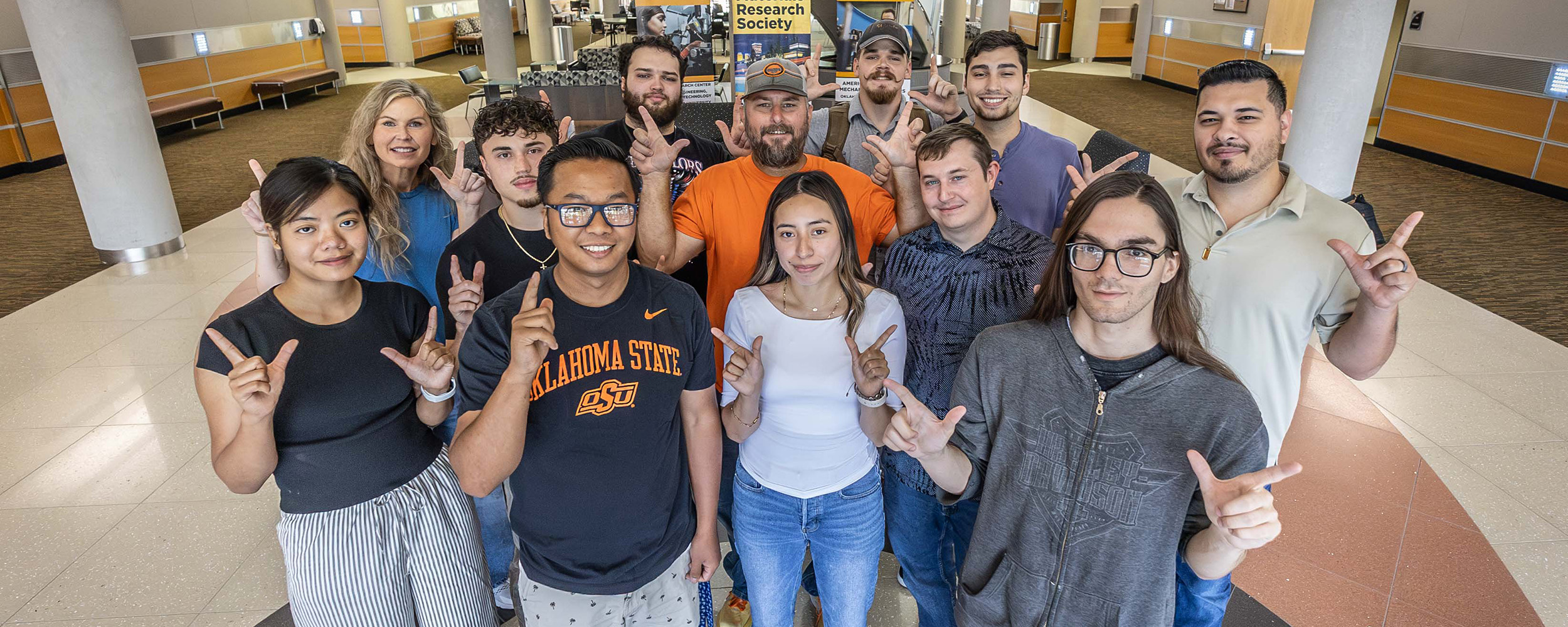 OSU-Tulsa students line up in rows in the Helmerich Research Center to pose for a classic "Go Pokes" photo on the first day of classes, fall 2025.