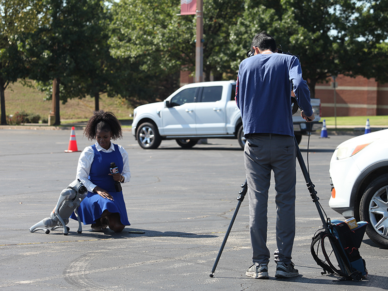 A KTUL reporter "interviews" an autonomous robot dog outside the Helmerich Research Center.