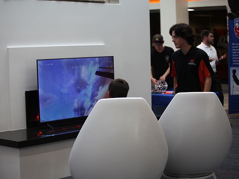 A student volunteer looks observes someone using the drone flight simulator.