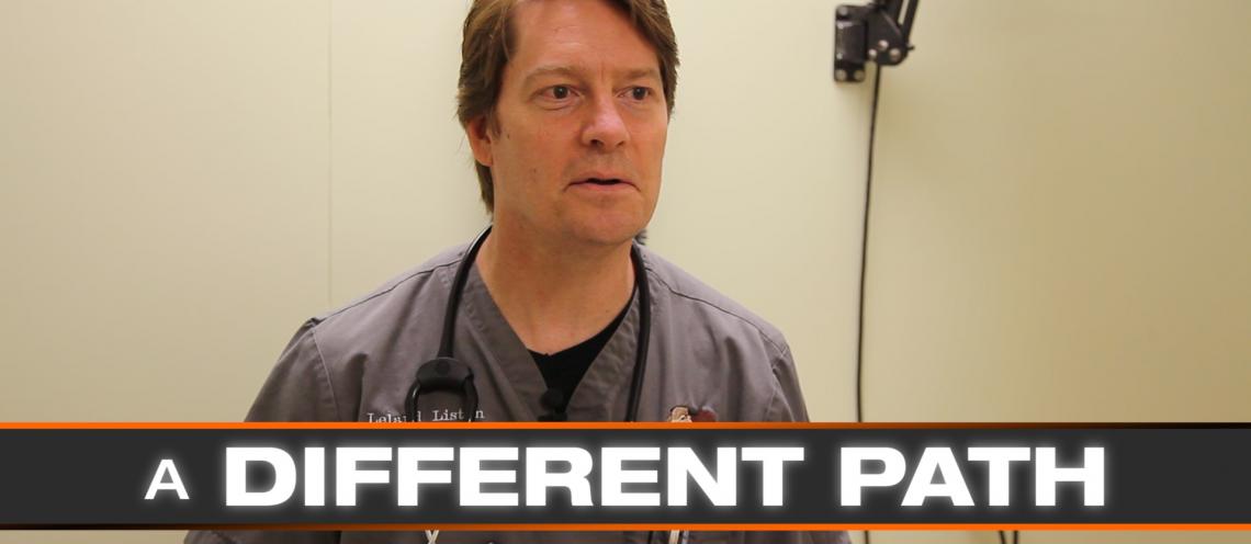 A Caucasian man with brown hair and a gray shirt poses for a picture.