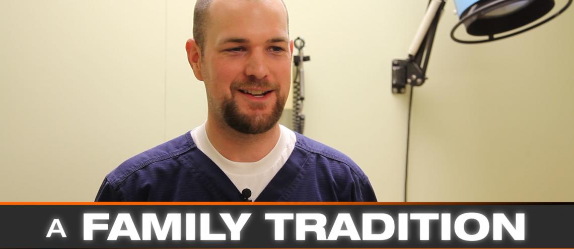 A Caucasian man with a goatee and purple shirt looks at the camera.