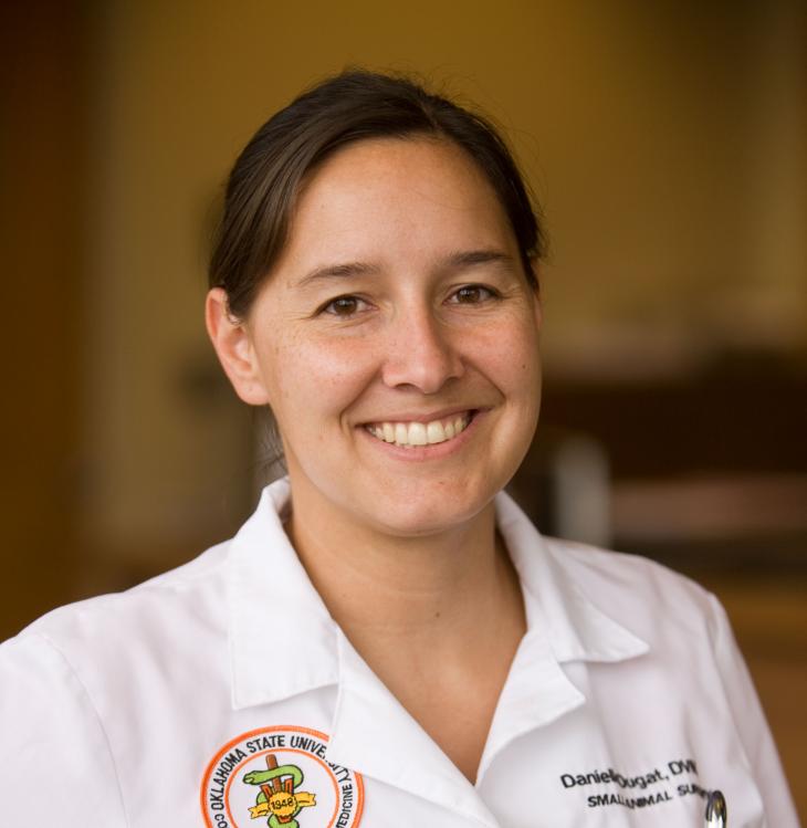 A woman wearing a white coat poses for a picture.