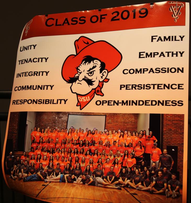 A brochure shows a picture of students wearing orange shirts.