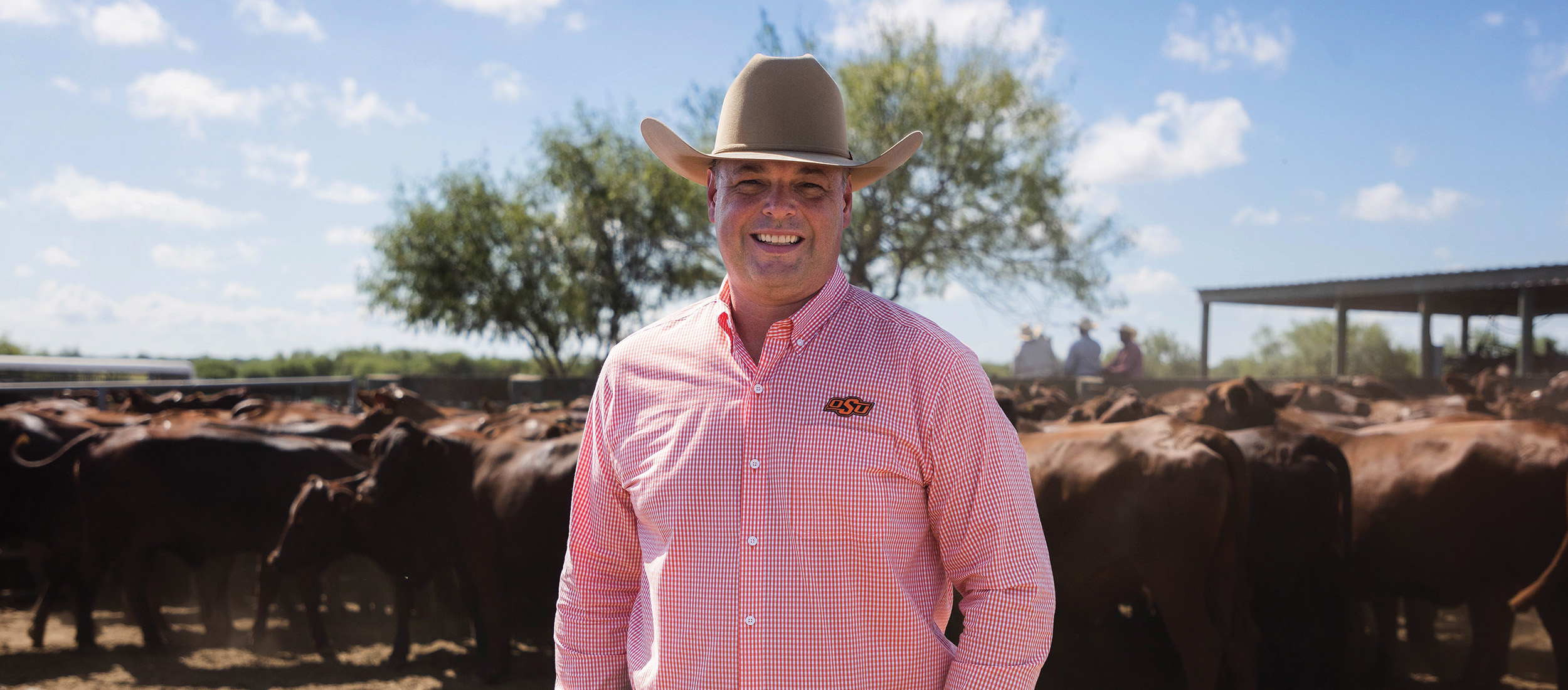 Robert Hodgen is smiling with cattle in the background.