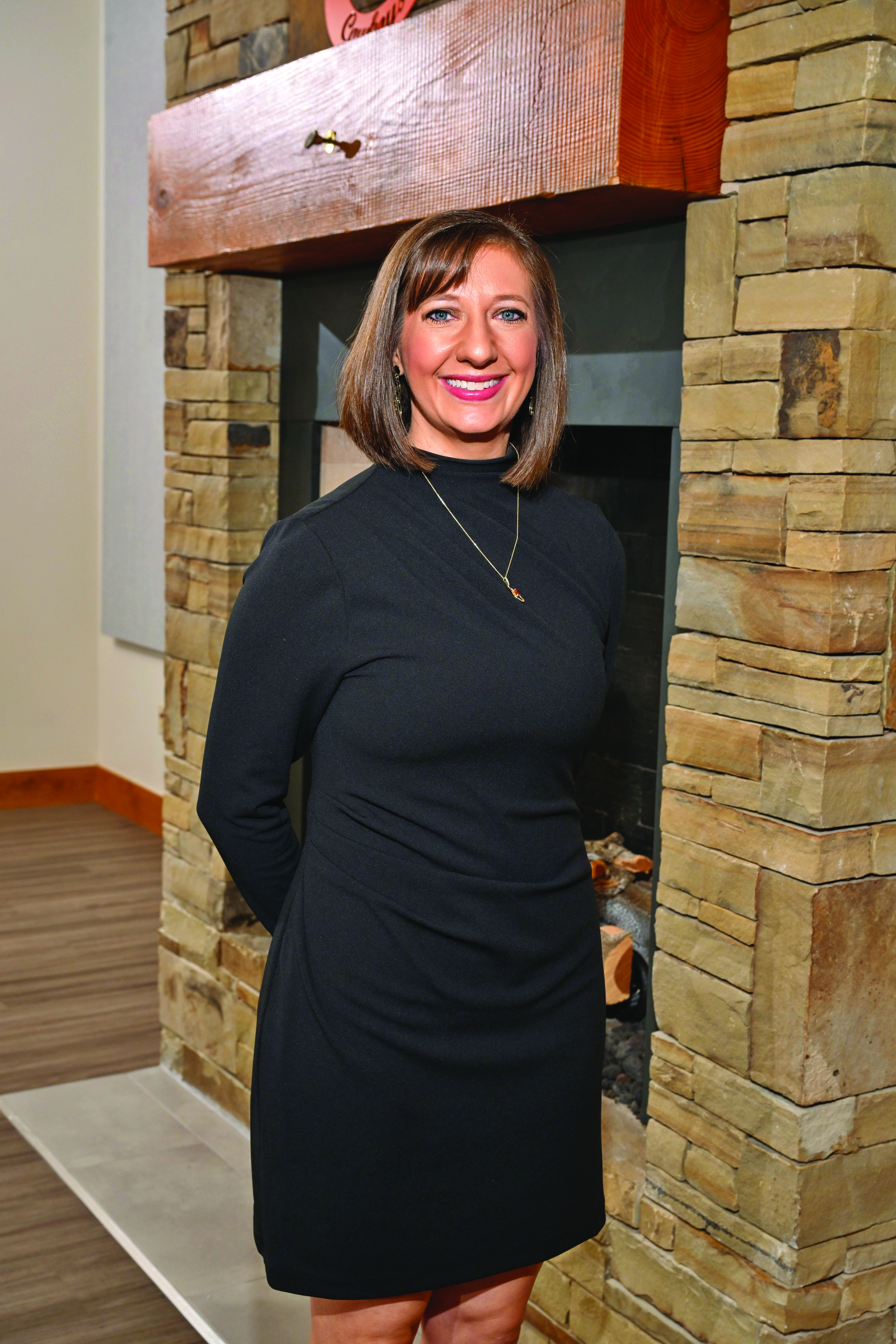 A person wears formal dress in front of a fireplace.