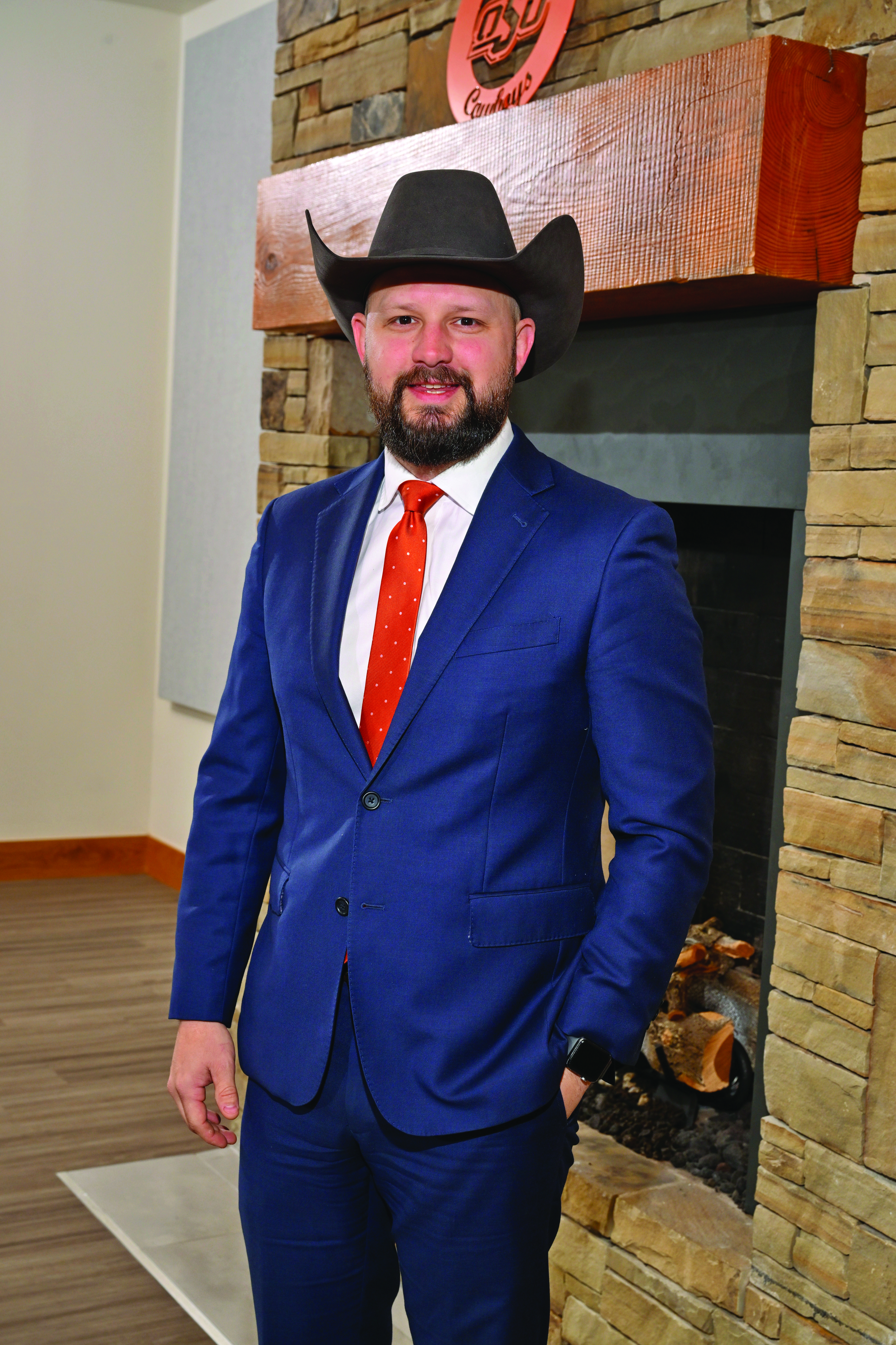 A person wears formal dress in front of a fireplace.