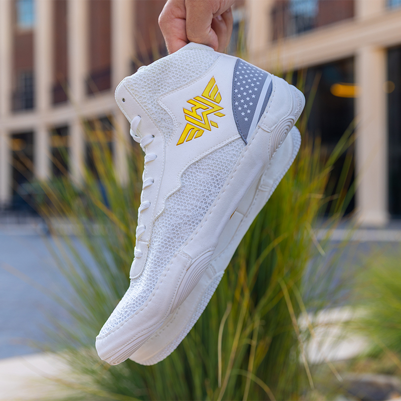 A pair of white wrestling shoes with the With Honor logo emblazoned on the side.