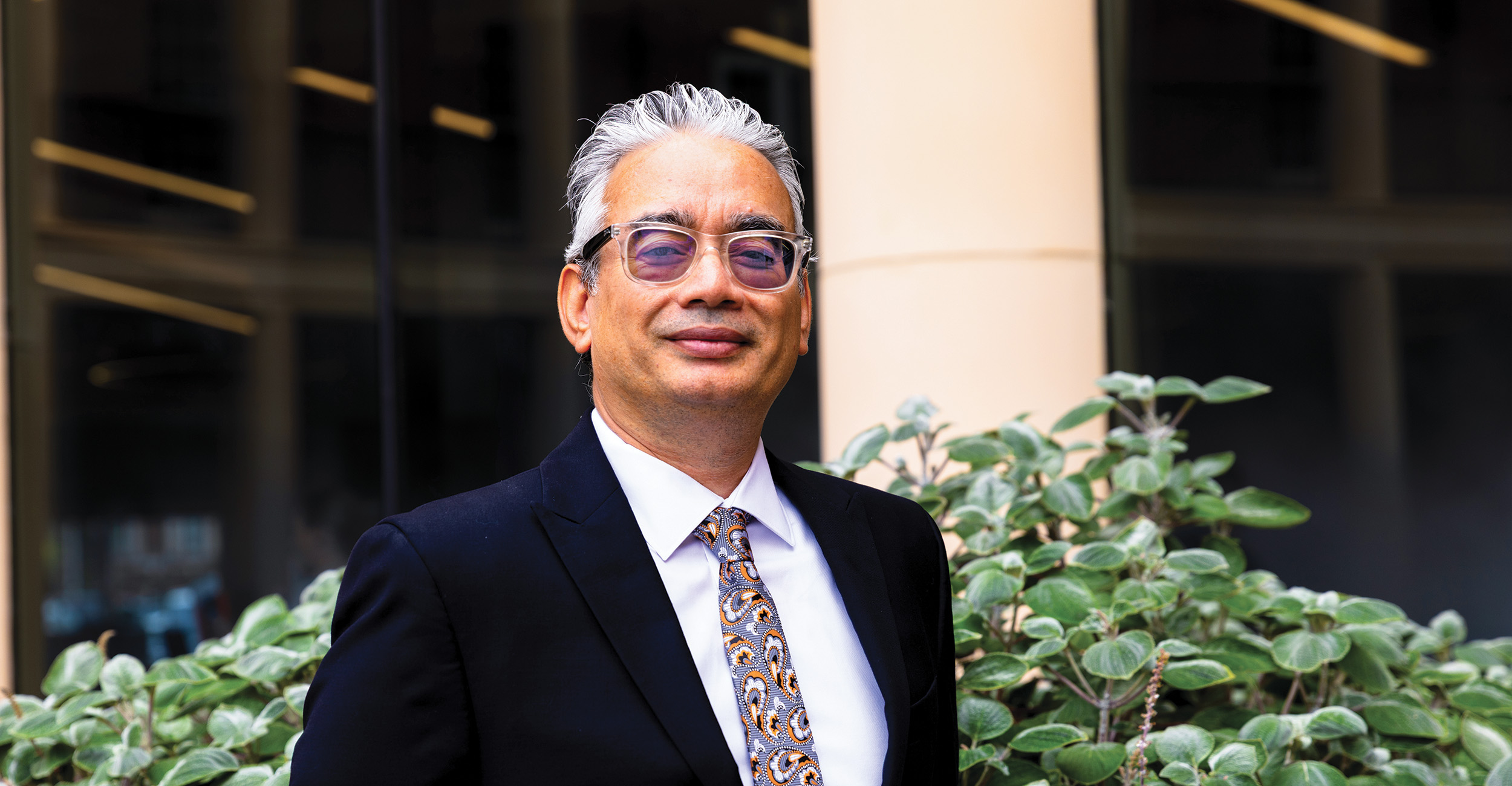 Dr. Brij Thapa poses in a business suit in the courtyard of the Business Building on the OSU campus.