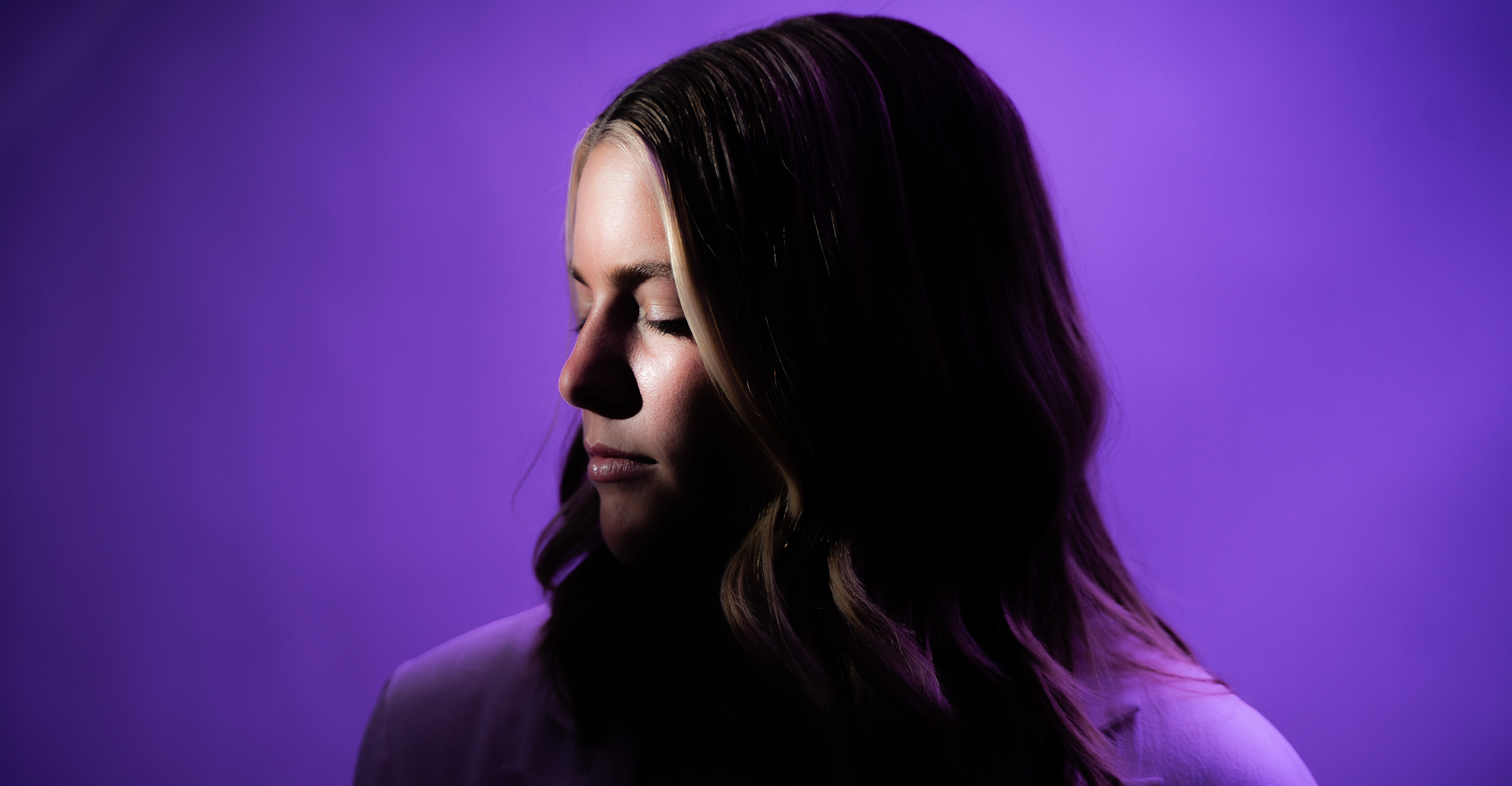 The profile of a young woman with a bright purple background