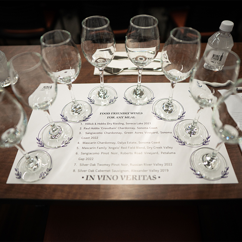 Wine glasses are laid out for samples on top of a sheet identifying which types of wine are in each glass.