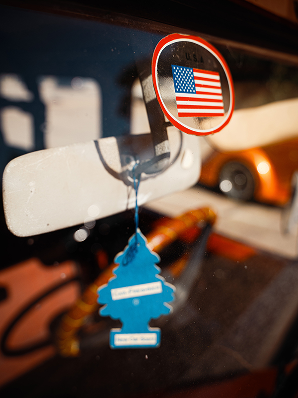 An American flag sticker and a pine-tree air freshener hang near the rear-view mirror of the FJ40.