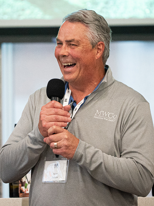 A smiling man speaking into a microphone about his wine company at the Wine Forum.