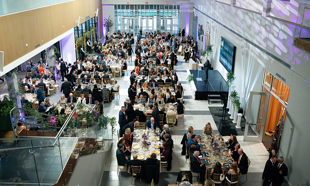 A photo of the Wine Forum Gala taken from the second floor balcony. Hundreds of patrons are enjoying the evening at their individual tables.