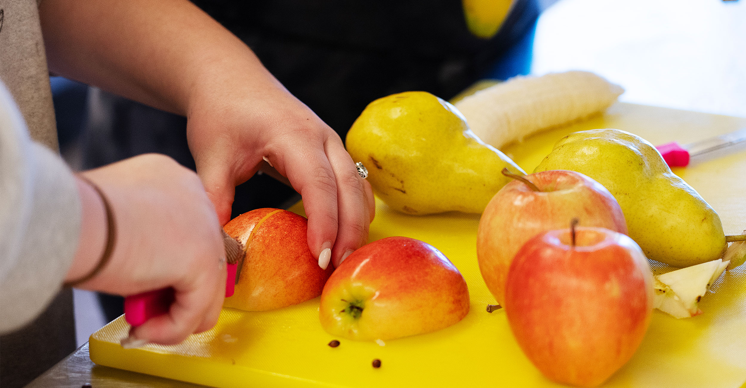 Fruit being sliced on cutting board
